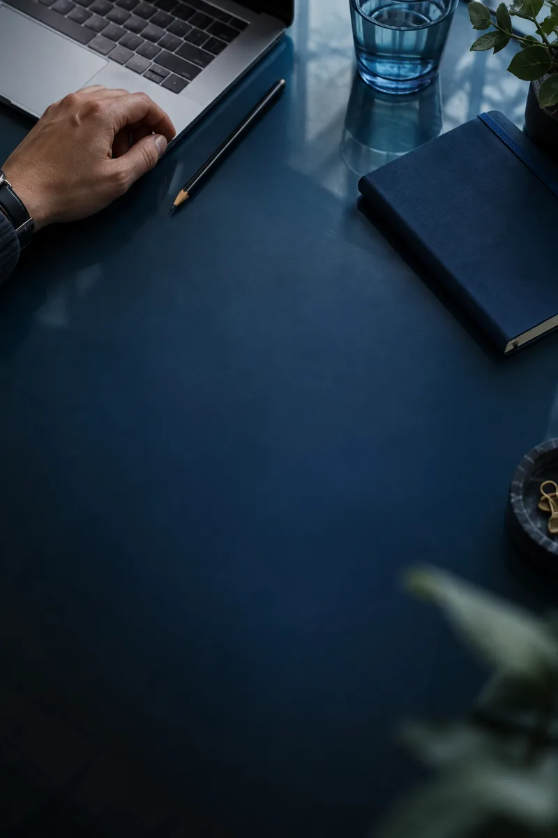 A custom editorial close-up of a developer’s working desk, keyboard and notebook.
